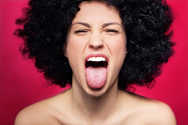 Frau mit dunklen Haaren zeigt Zunge