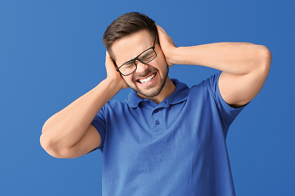 Junger Mann mit Brille hält sich Ohren zu