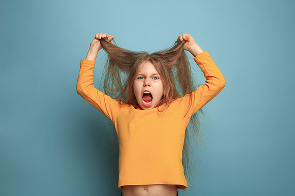 Mädchen im gelben Pulli rauft sich schreiend Haare