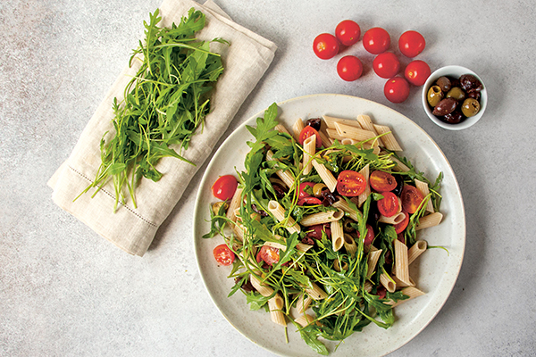 Teller mit Nudelsalat, Rucola, Tomaten, Oliven